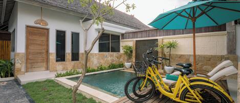 Una casa con piscina, terraza de madera y una bicicleta estacionada afuera.