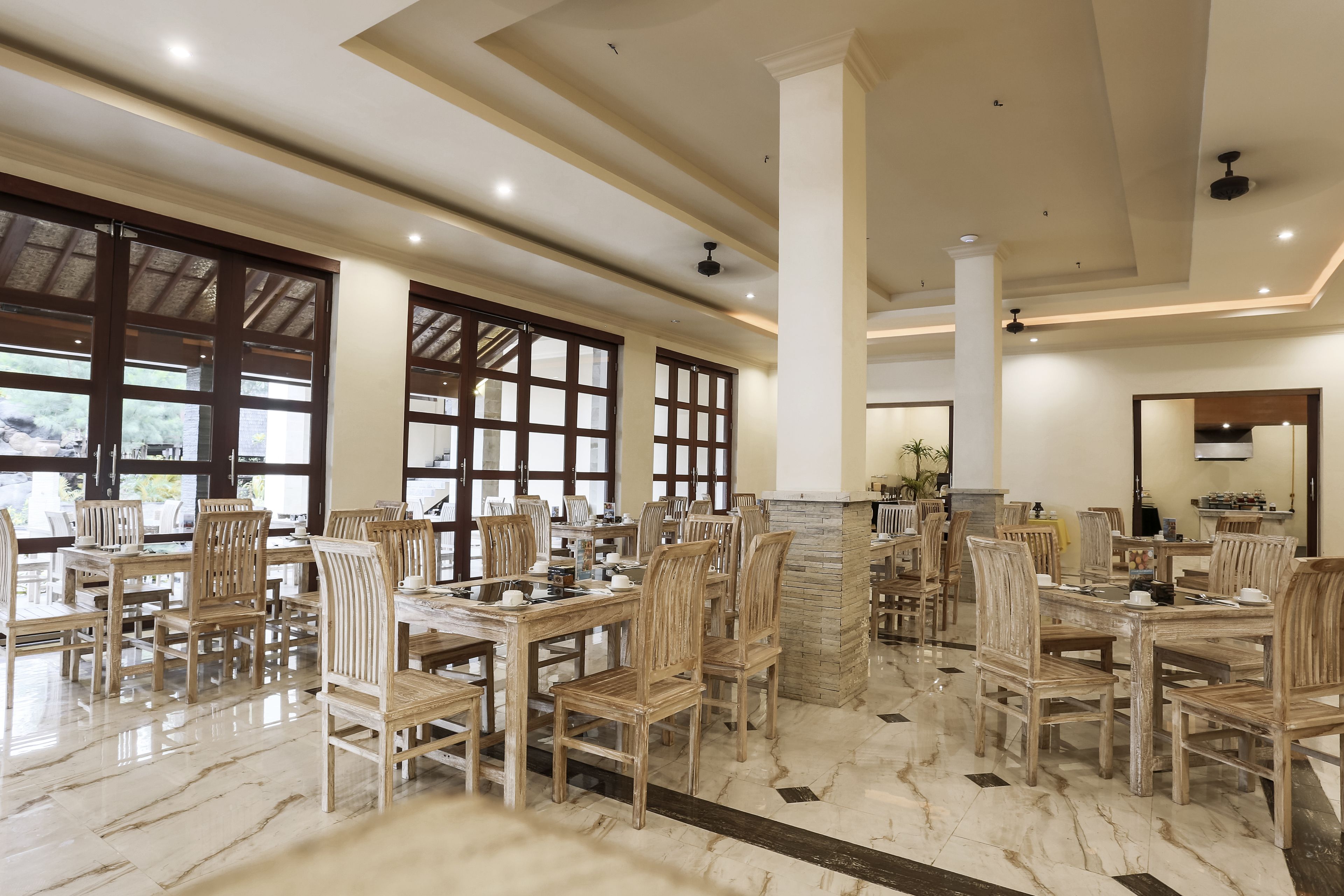 A spacious dining area with wooden tables and chairs, large windows, and a stone fireplace.