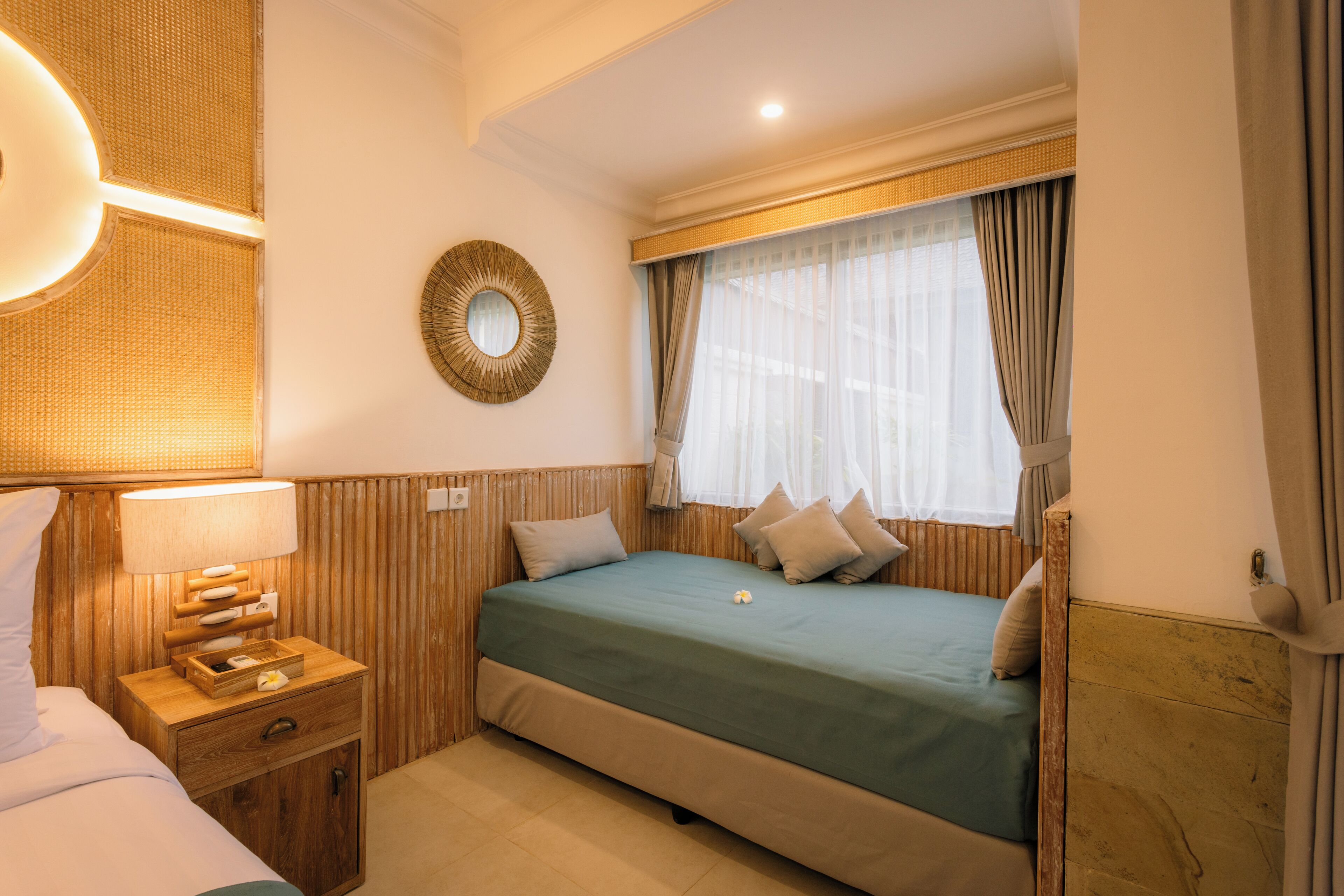 Ein Hotelzimmer mit Bett, Nachttisch, Lampe und Spiegel an der Wand.
