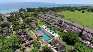 Een resort met meerdere bungalowgebouwen, een centraal zwembad en uitzicht op de oceaan.
