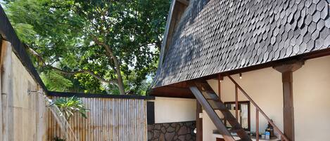 A traditional Japanese-style building with a wooden exterior, a stone wall, and a tiled patio area.