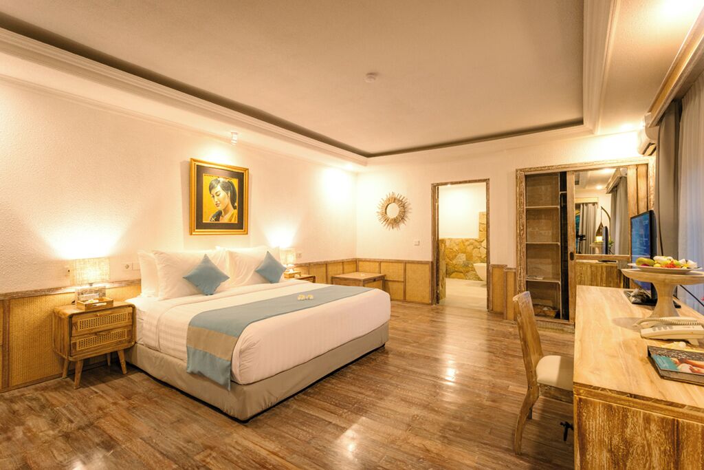 Habitación de hotel con cama, mesitas de noche, escritorio y espejo.