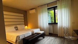 Un dormitorio moderno con una cama grande, un banco, una silla y una ventana con cortinas.
