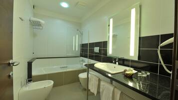 A modern bathroom with a bathtub, toilet, sink, and a large mirror.