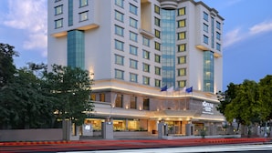 A multi-story hotel with a modern facade, large windows, and a prominent entrance with flags.