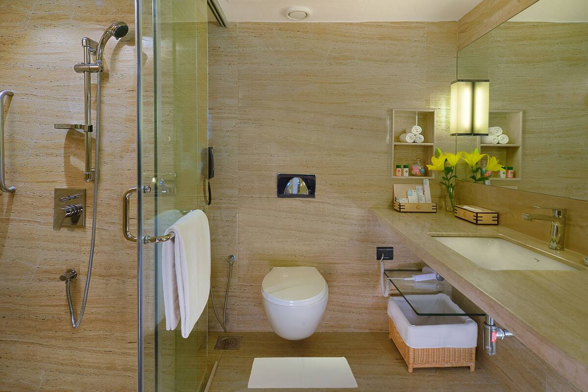Un baño moderno con ducha envuelta en vidrio, inodoro y tocador con espejo.