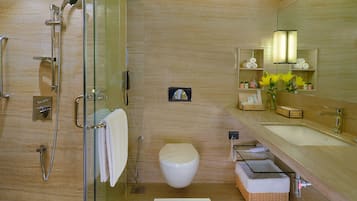 A modern bathroom with a glass-enclosed shower, a toilet, and a vanity with a mirror.
