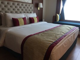A neatly made bed with a tufted headboard, a bedside lamp, and a window with curtains.