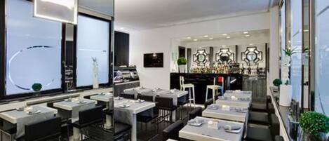 A modern restaurant with a long counter, multiple tables, and a bar area.
