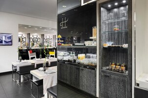 A modern hotel lobby with a reception desk, seating area, and a buffet counter.