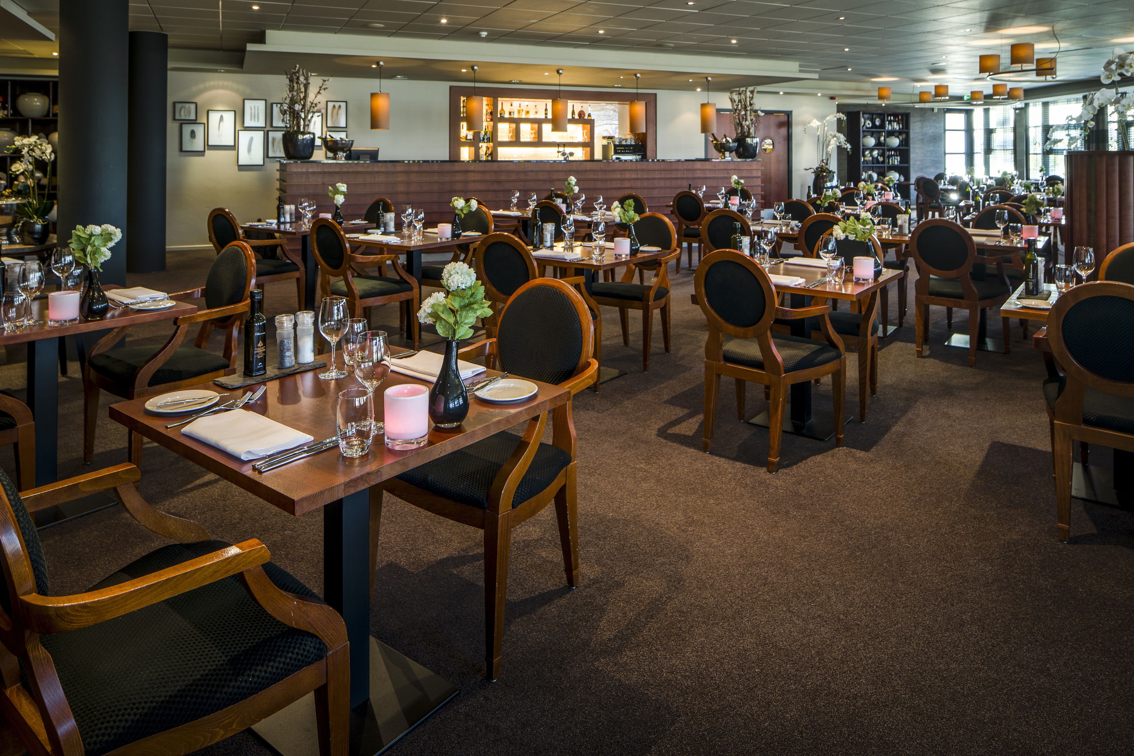 A restaurant with multiple tables and chairs, a bar area, and a well-lit interior.