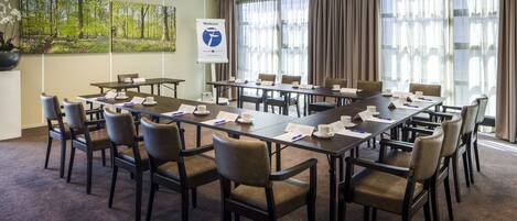 A conference room with a large table, multiple chairs, and a banner on the wall.