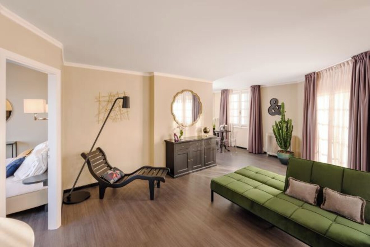 Uma sala de estar moderna com um sofá verde, um banco de madeira, um armário escuro e um espelho grande.