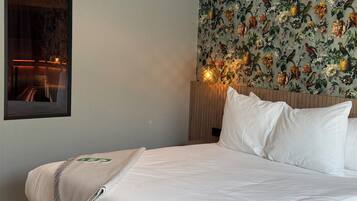 Una habitación de hotel con una cama, un espejo y papel tapiz floral.