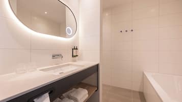Een moderne badkamer met een grote spiegel, twee wastafels, een douche en een bad.
