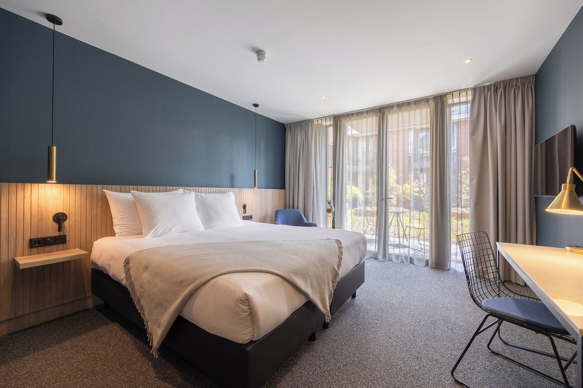 Ein modernes Hotelzimmer mit einem großen Bett, einem Schreibtisch und einem Stuhl.