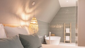 Une chambre moderne avec un grand lit, une lampe de chevet, une baignoire et une échelle en bois.