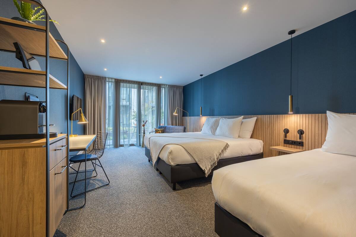 Ein modernes Hotelzimmer mit zwei Betten, einem Schreibtisch und einem Stuhl.