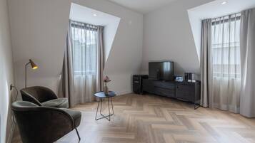 Een moderne woonkamer met een bank, een bijzettafeltje, een televisie en een visgraatvloer.