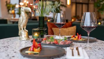 Una mesa de comedor con una escultura decorativa de un pájaro, un florero con bayas rojas y dos copas de vino.