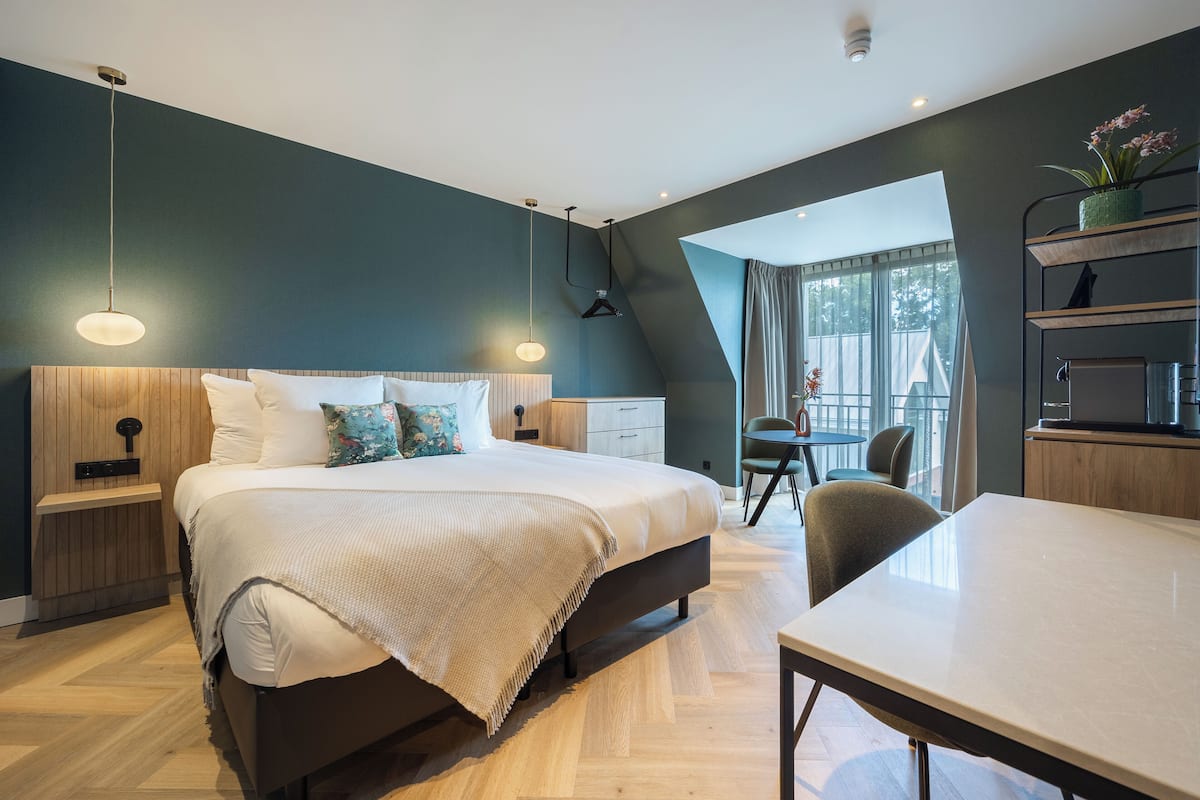 Ein modernes Schlafzimmer mit einem großen Bett, Nachttischen, einem Schreibtisch und einem Sessel.