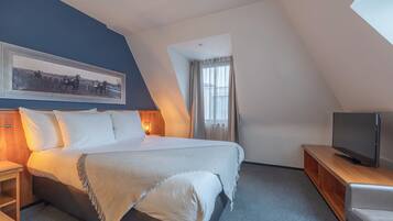 Una habitación de hotel moderna con una cama grande, un televisor sobre un soporte de madera y un cuadro enmarcado en la pared.