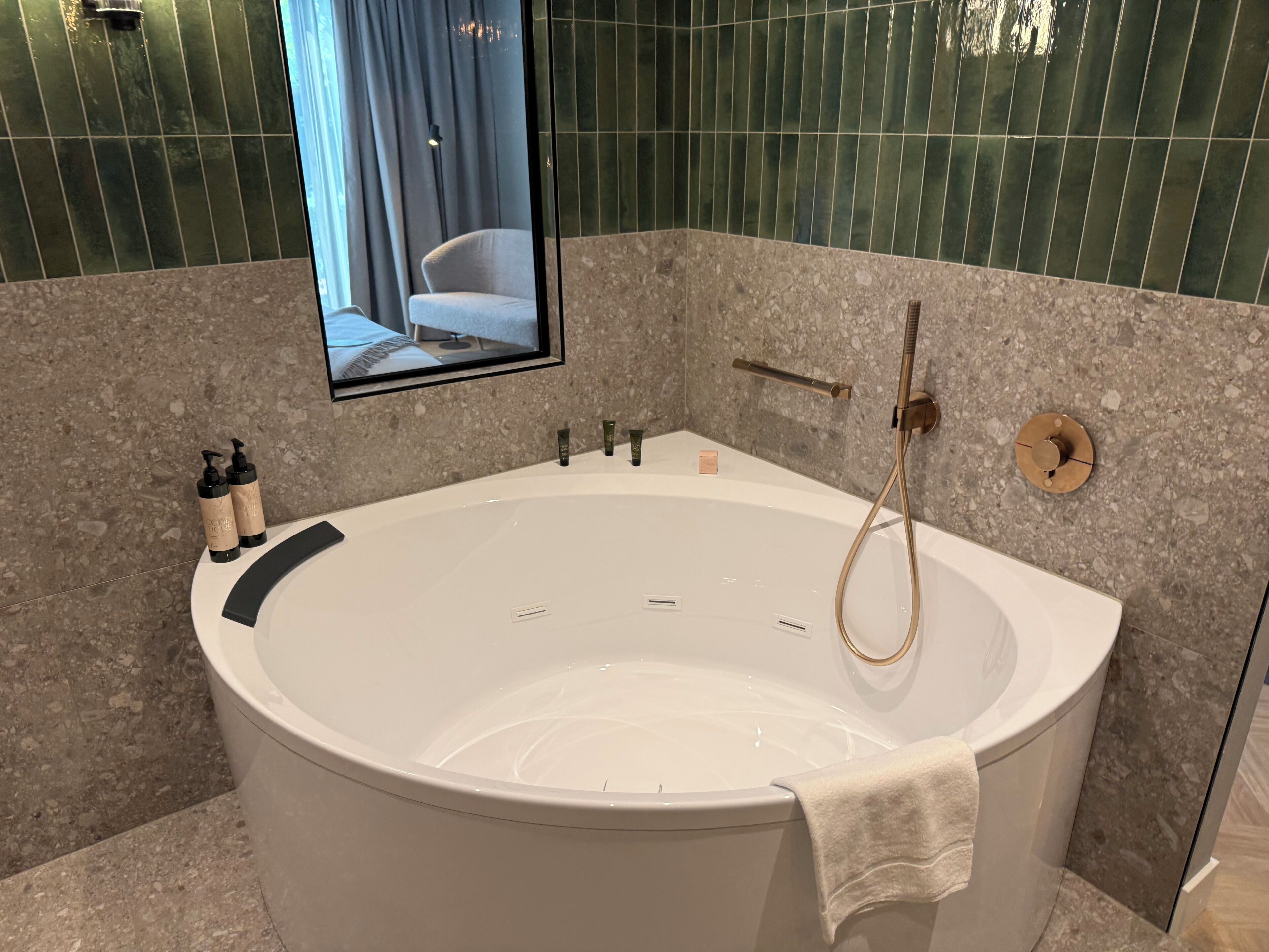 Une salle de bain moderne avec une baignoire sur pieds, un miroir fixé au mur et des articles de toilette disposés sur le côté.