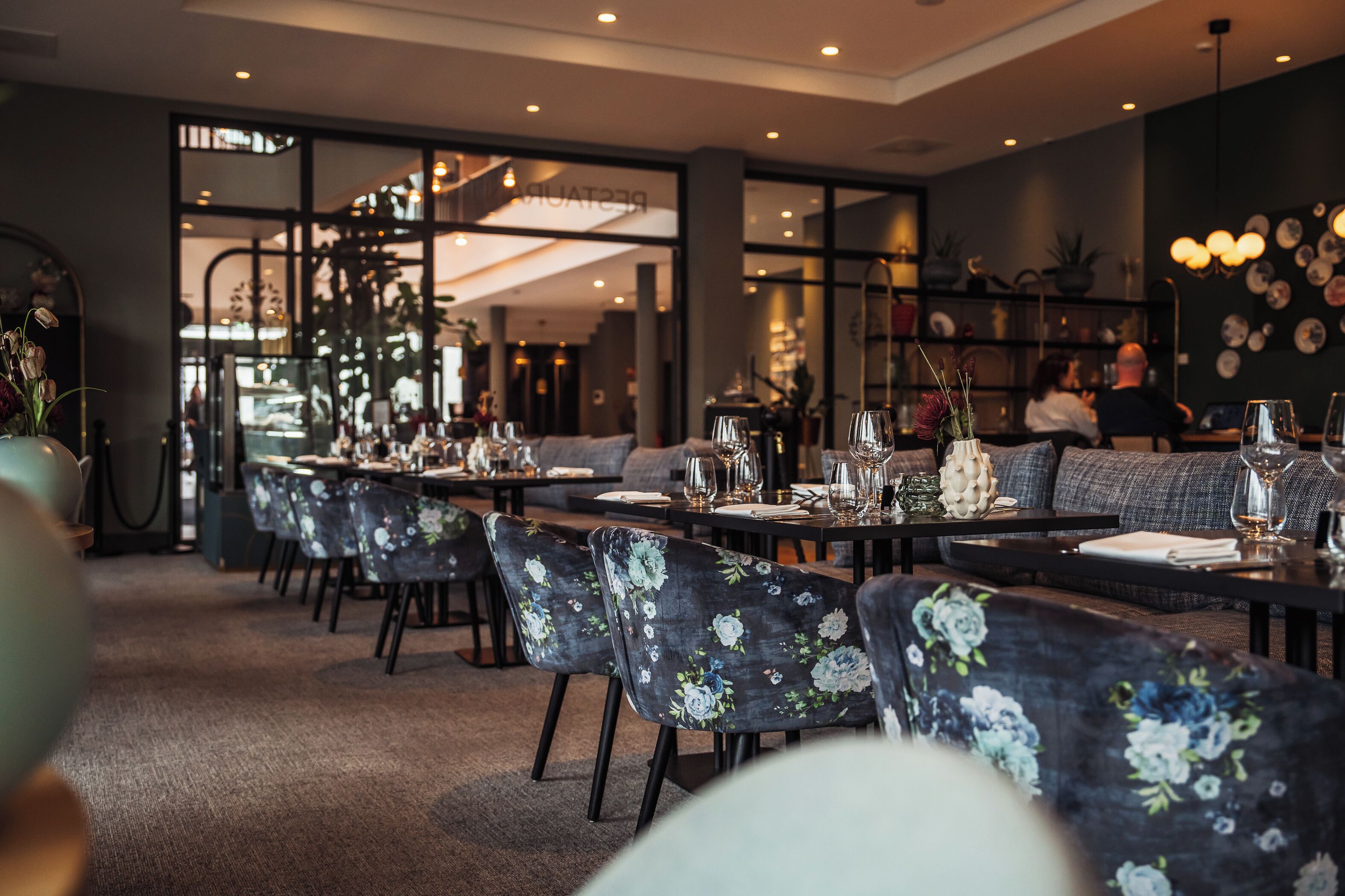 A restaurant with floral-patterned chairs and tables set for dining.