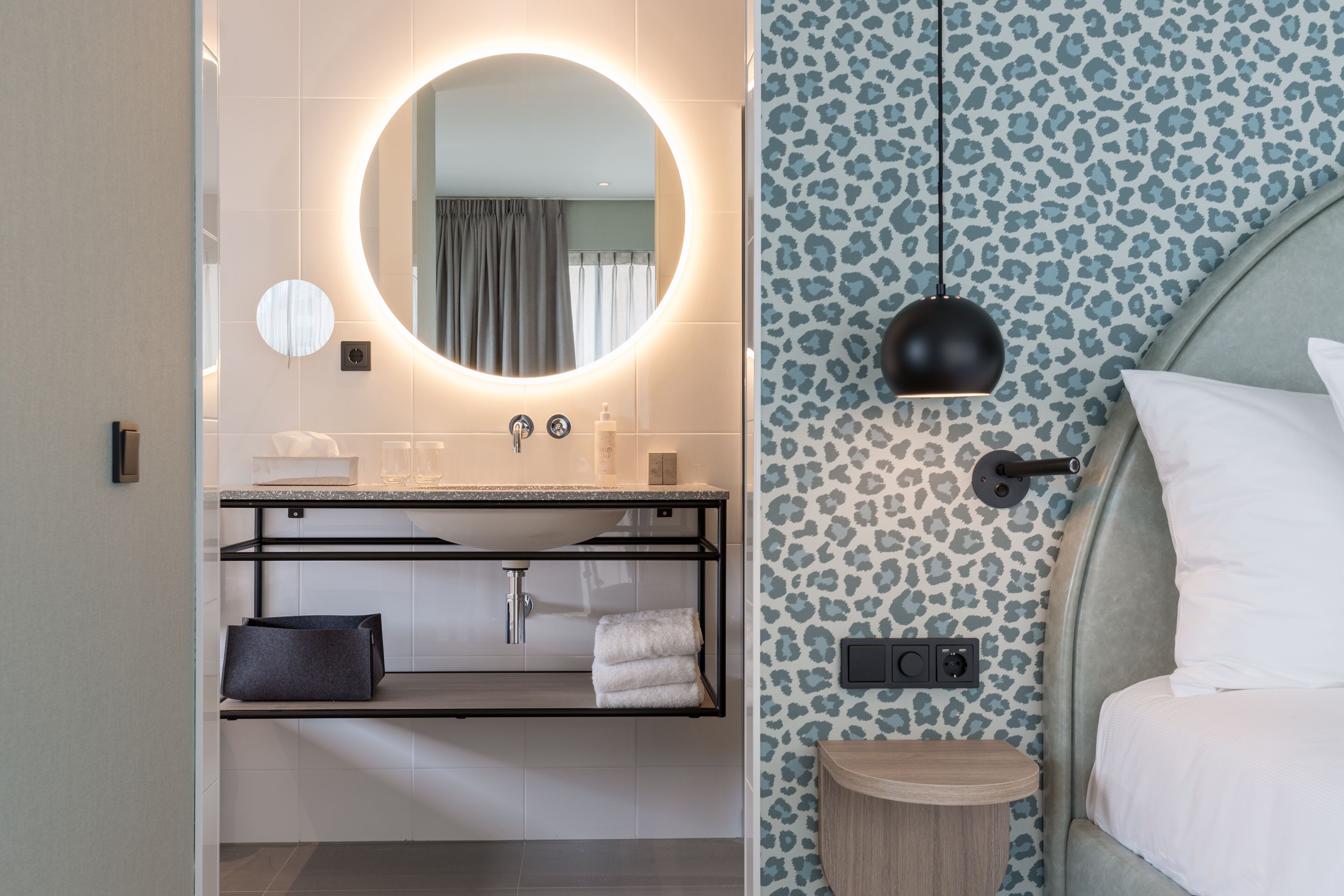 A modern bathroom with a round mirror, a sink, and a towel rack.