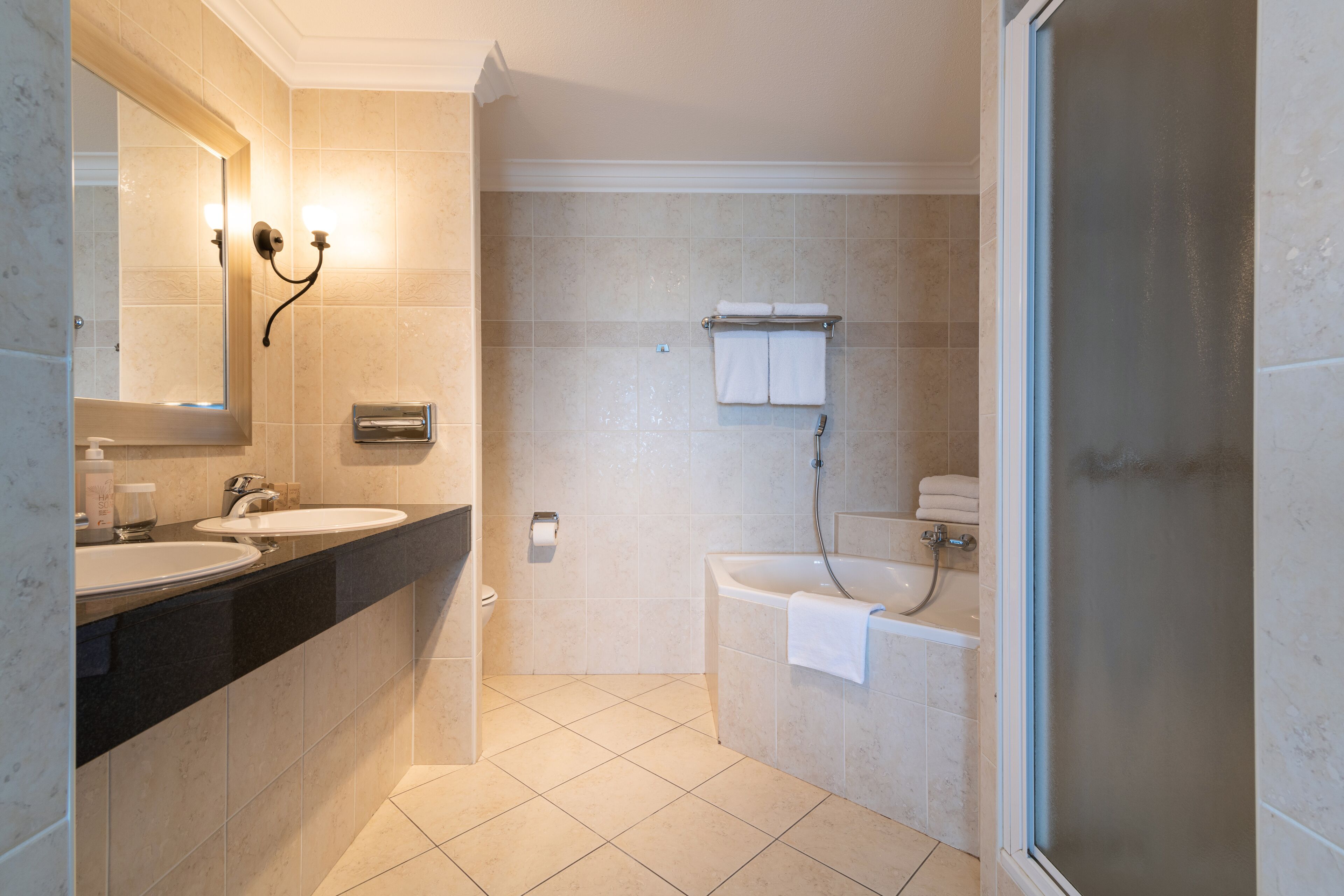 A modern bathroom with two sinks, a bathtub, and a shower.