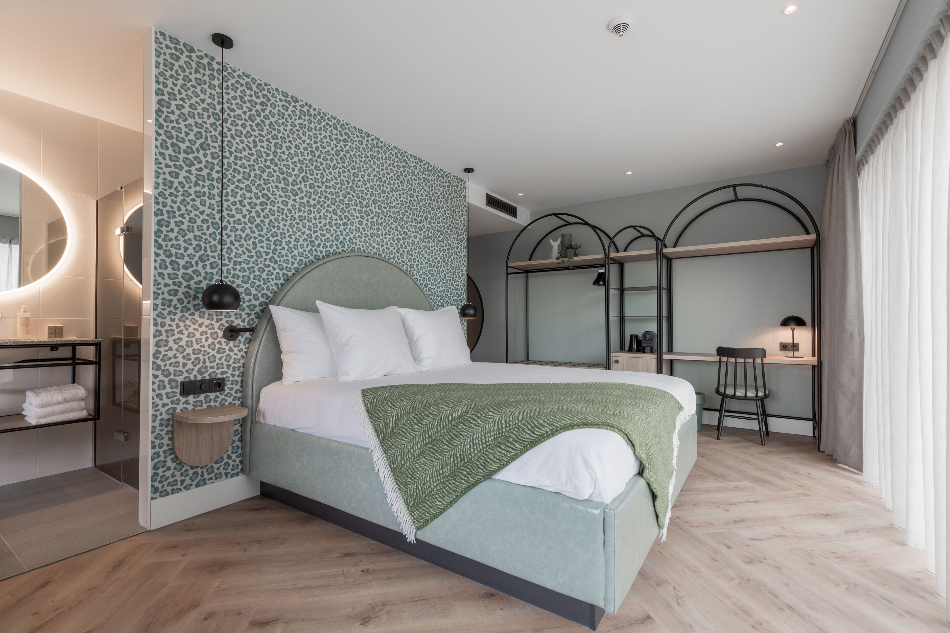 Un dormitorio moderno con una cama, un escritorio y un espejo.