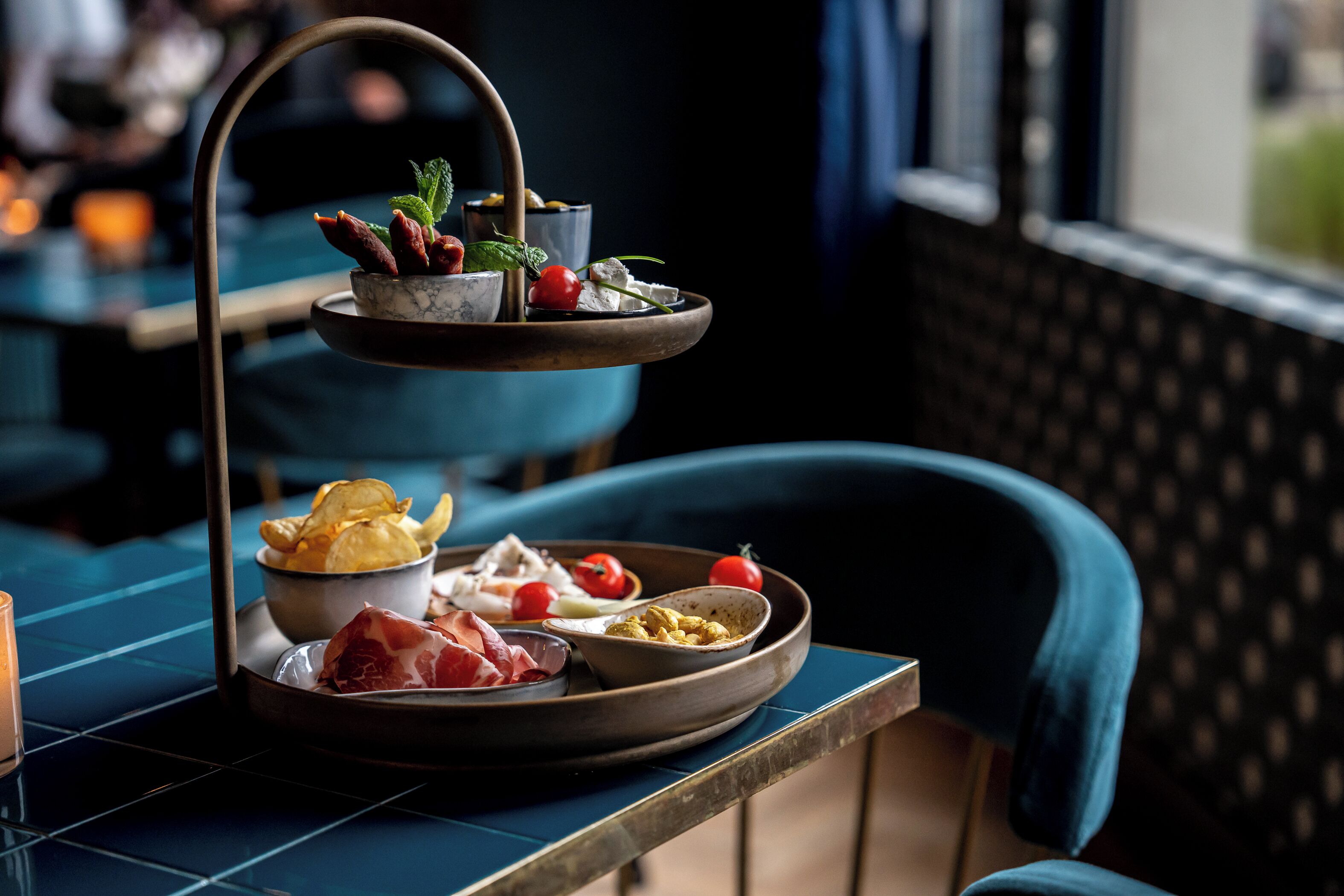 A tiered serving tray with various food items on a table in a restaurant setting.