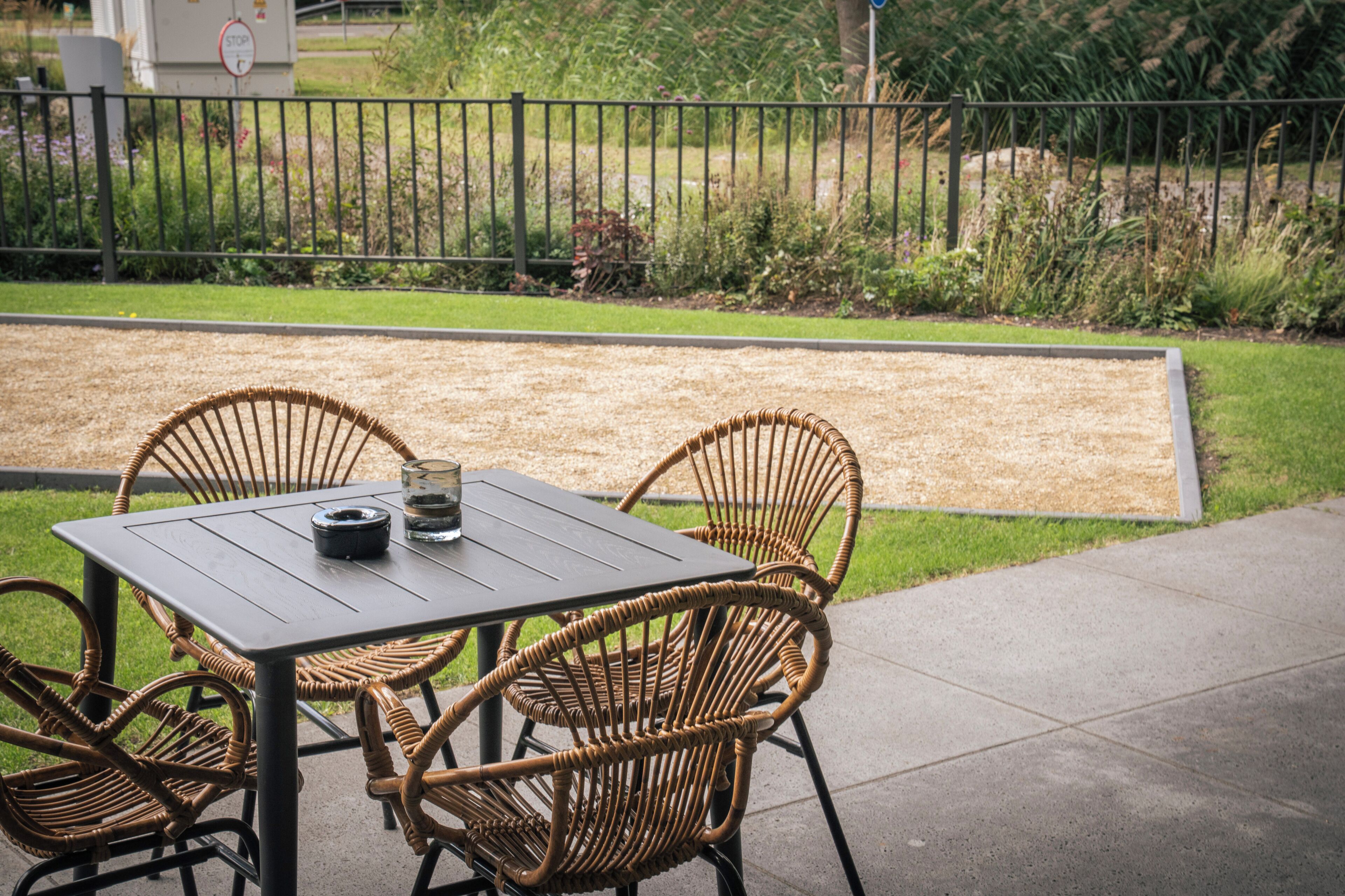 An outdoor seating area with a table and four wicker chairs.