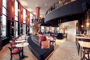 A modern interior with a bar area, seating arrangements, and large windows.