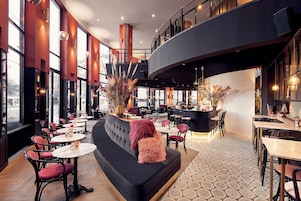Un interior moderno con una zona de bar, espacios de asiento y amplios ventanales.