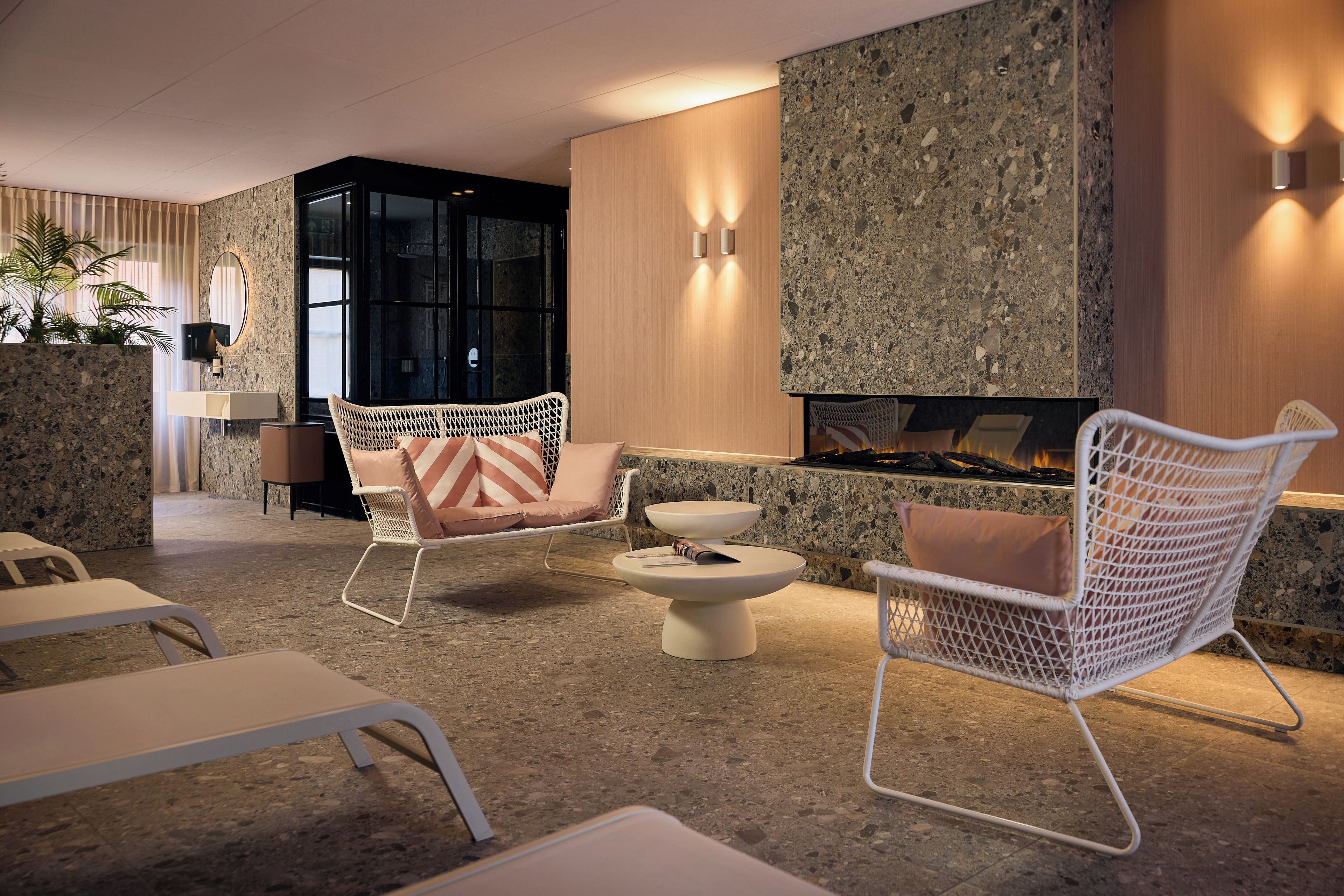 A modern lounge area with wicker chairs, a round table, and a built-in fireplace.
