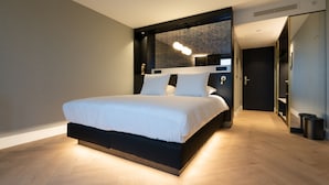A modern bedroom with a large bed, a built-in wardrobe, and a mirror. - Theaterhotel De Oranjerie (Roermond)