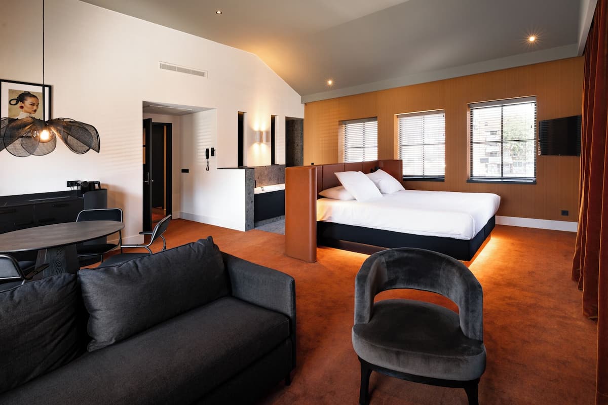 Ein modernes Hotelzimmer mit einem großen Bett, einem Schreibtisch, einer Couch und einem Sessel.