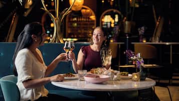 Two people seated at a round table with a bottle of wine, a glass of water, and a plate of food.