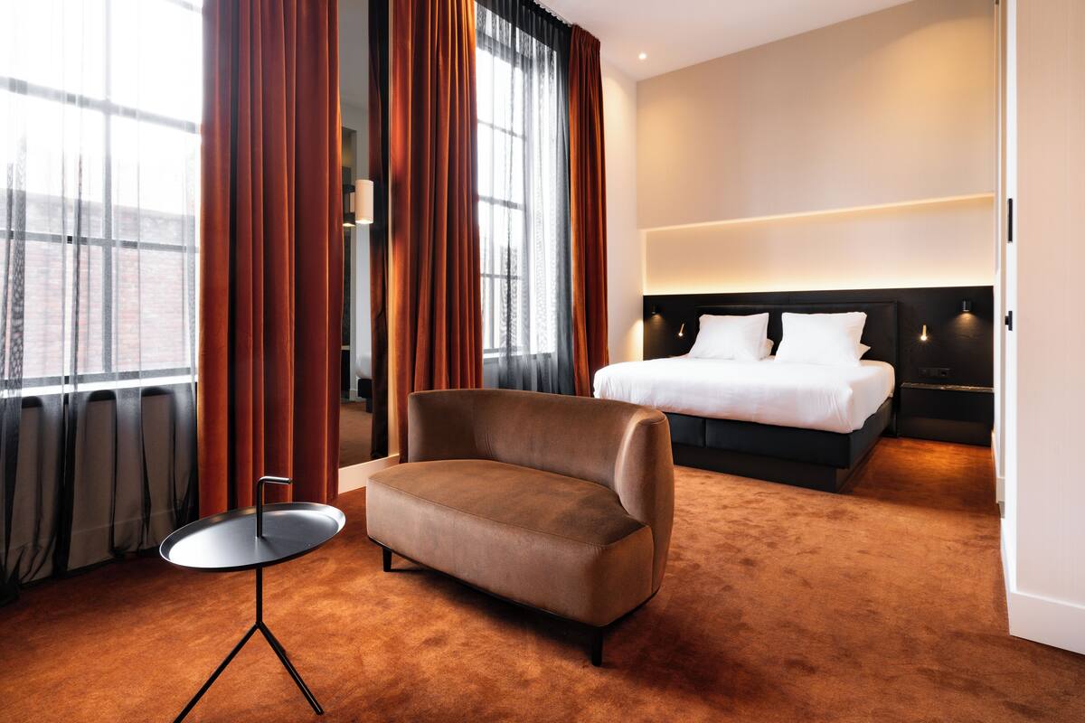 Ein Hotelzimmer mit einem großen Bett, einem braunen Sofa und einem kleinen Tisch.