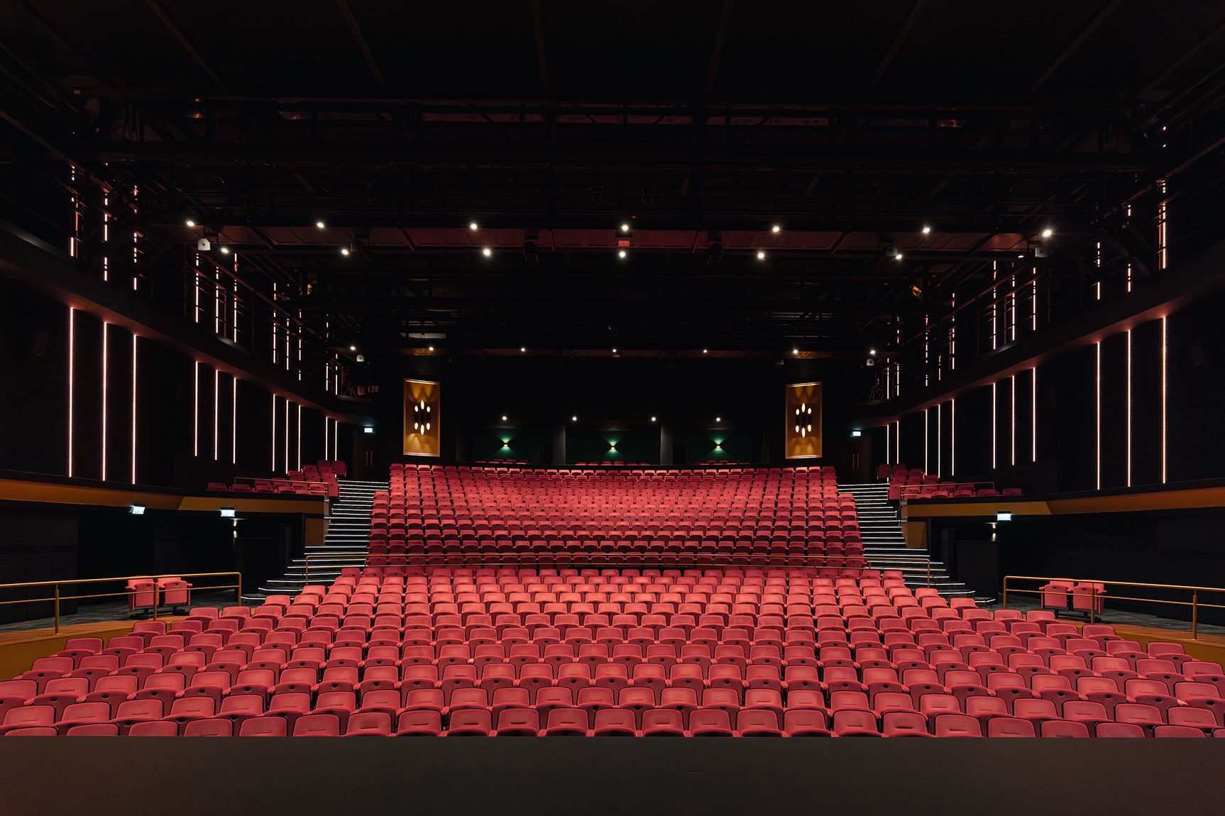 A theater with rows of red seats, a central stage, and a dark interior.