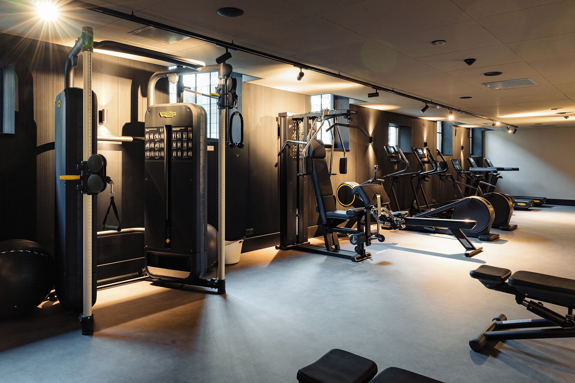 Uma academia com diversos equipamentos de exercícios, incluindo máquinas de peso e esteiras.