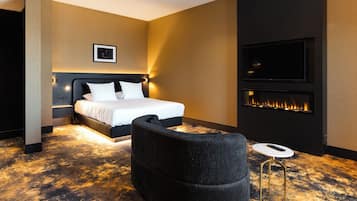 Una habitación de hotel moderna con una cama grande, un televisor montado en la pared y una chimenea.