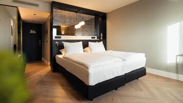 Ein modernes Hotelzimmer mit einem großen Bett, einem dunklen Kopfteil und einem einzigartigen Wandbild darüber.