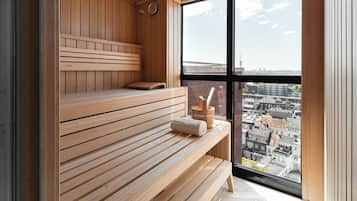A wooden sauna with benches and a view of the city through large windows.
