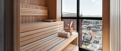 Uma sauna de madeira com bancos e vista da cidade através de grandes janelas.