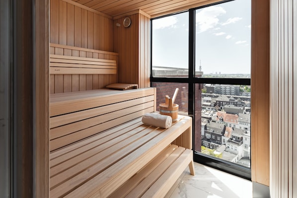 Una sauna de madera con bancos y vistas de la ciudad a través de amplias ventanas.