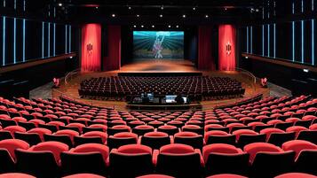 A theater with a central stage, red curtains, and rows of red seats.