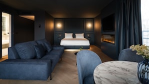 A modern hotel room with a bed, a sofa, a chair, and a small table. - Theaterhotel De Oranjerie (Roermond)