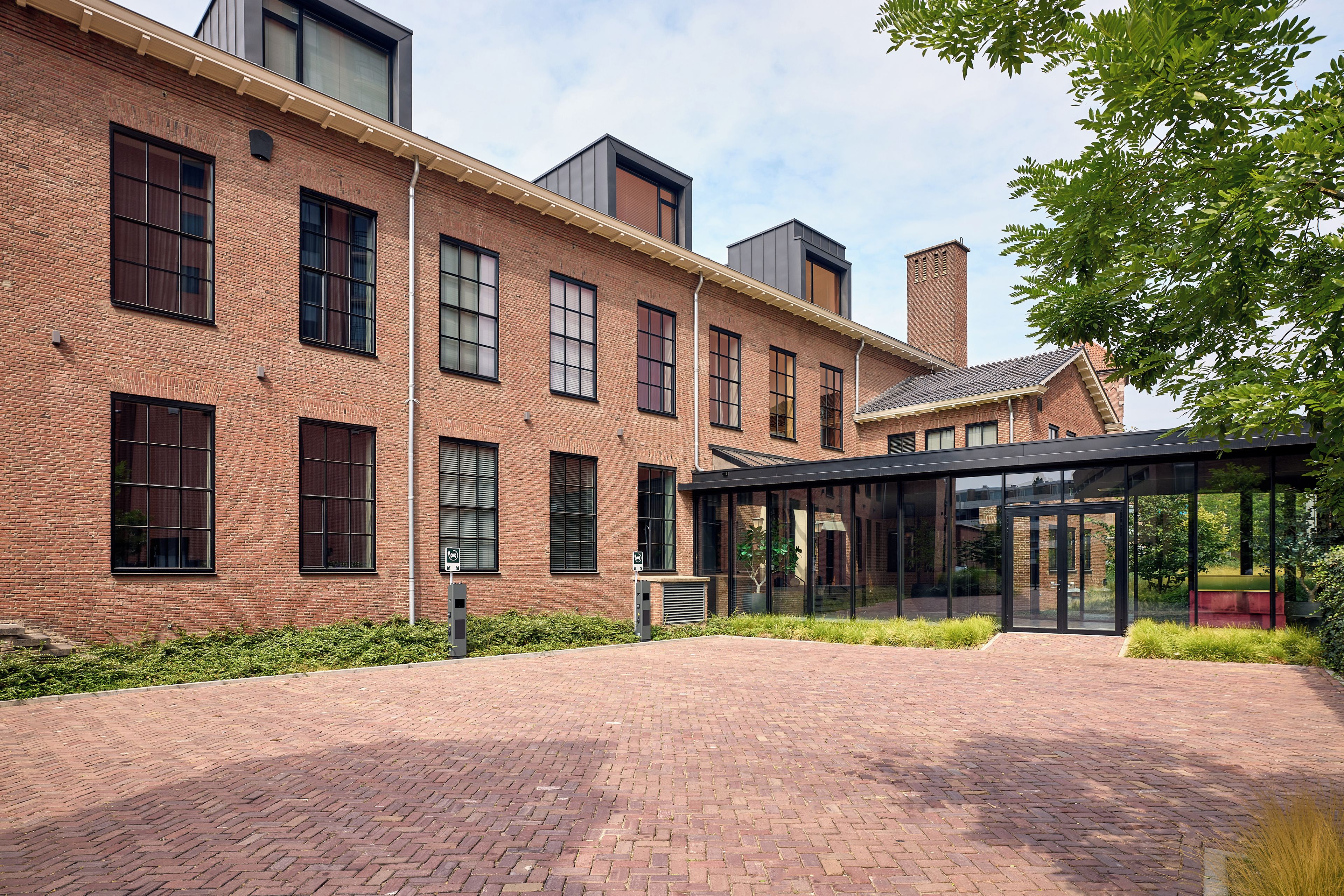 A brick building with large windows and a covered outdoor area.